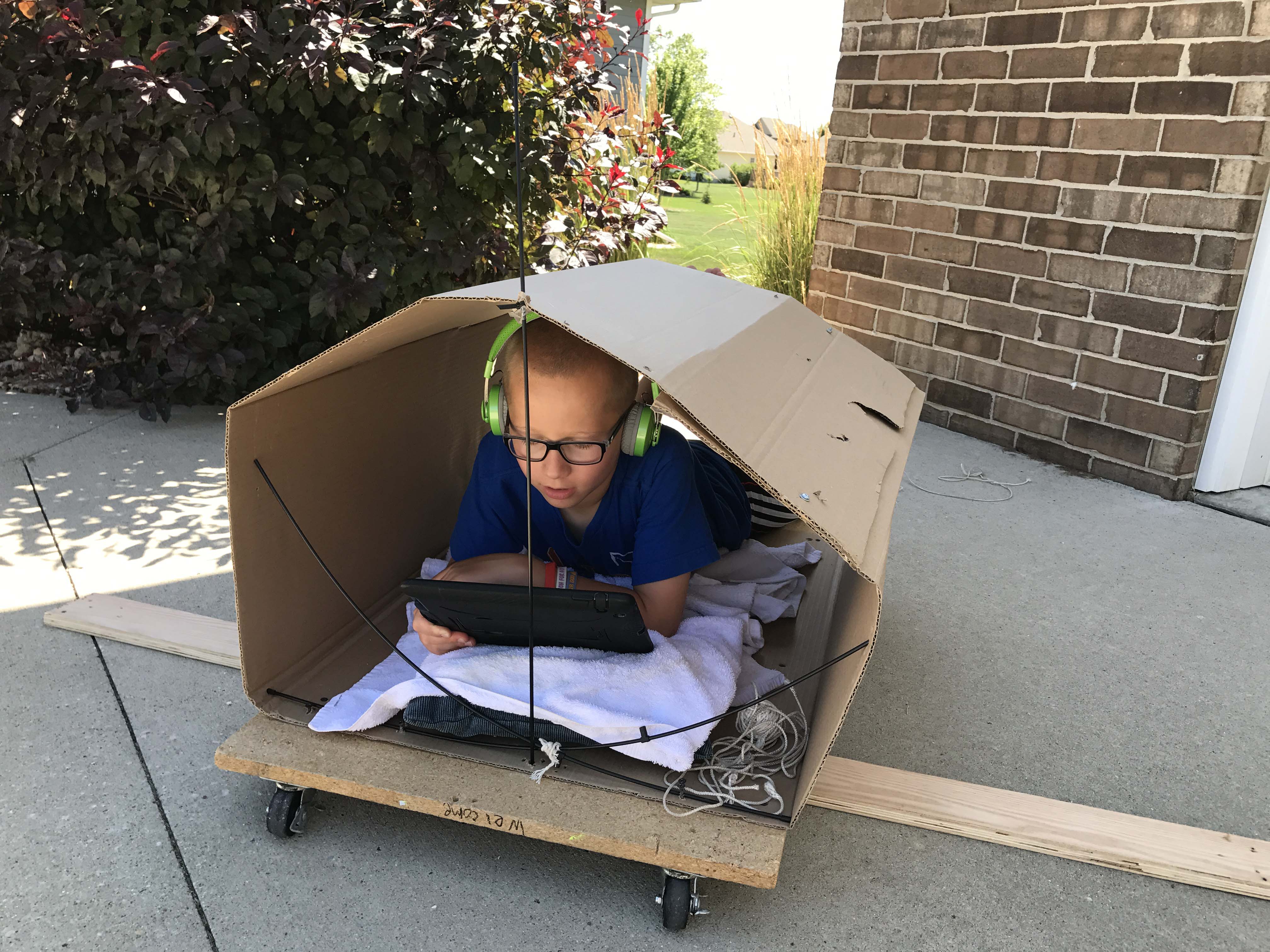Dyslexic student ear reading in a fort he built outside on a summer's day.